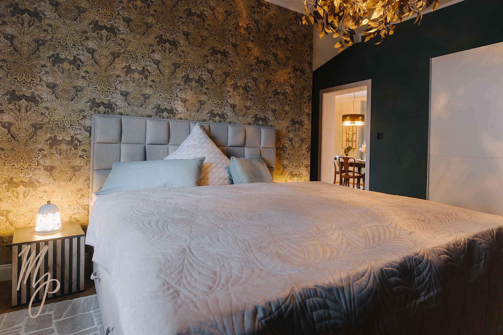Schlafzimmer mit goldener Ornament-Tapete und Boxspringbett